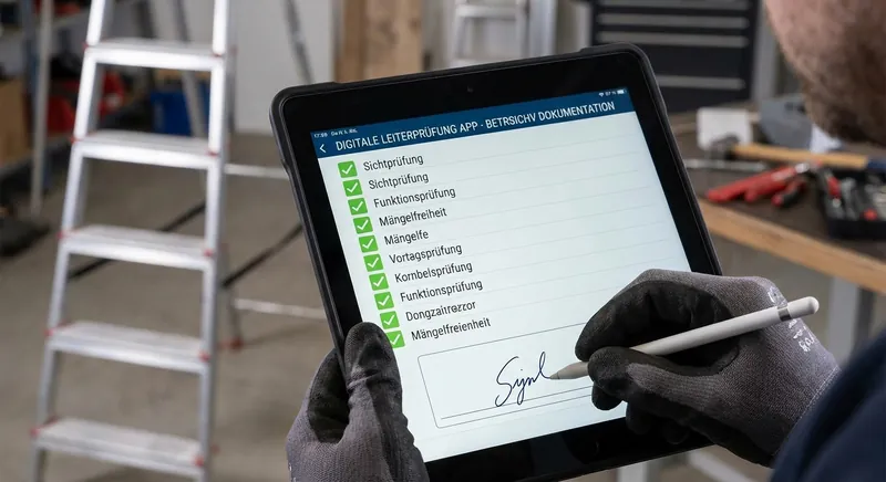 Befähigte Person prüft eine Stehleiter mit einem Tablet und der HAILO Inspect App, Prüfplakette wird angebracht